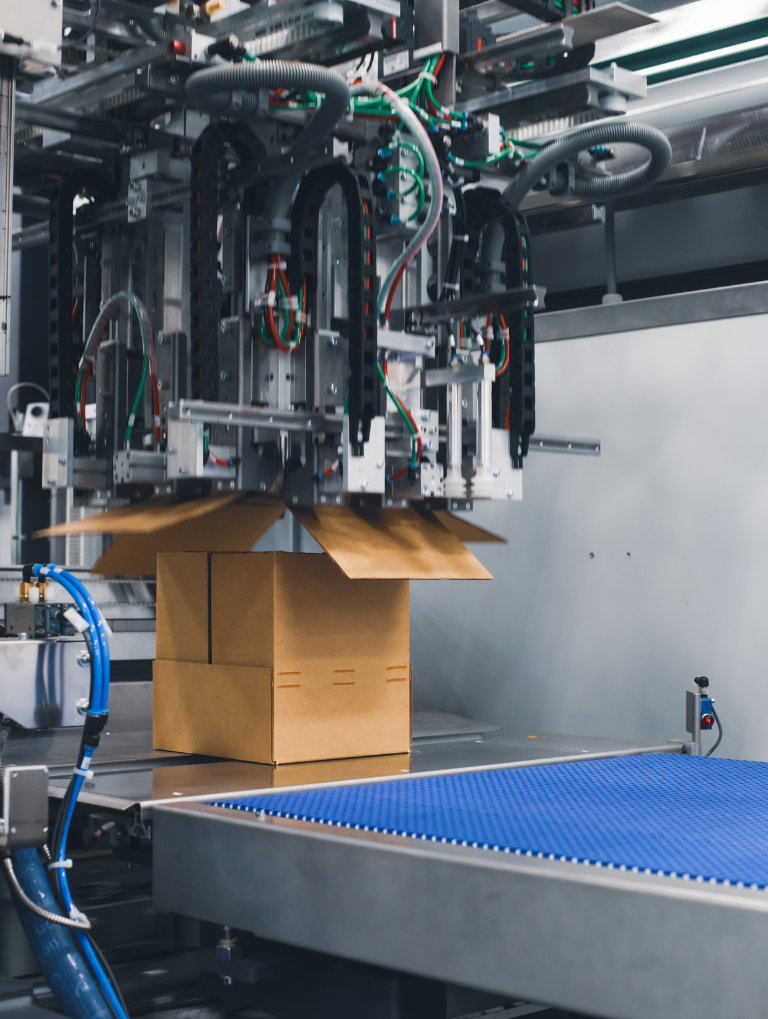 Product on a conveyor system with an automated machine building a box around the product